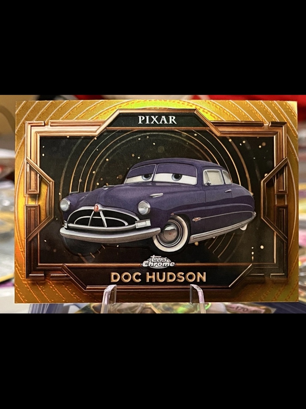 Topps Pixar Doc Hudson Trading Card — Purple & Gold Holographic